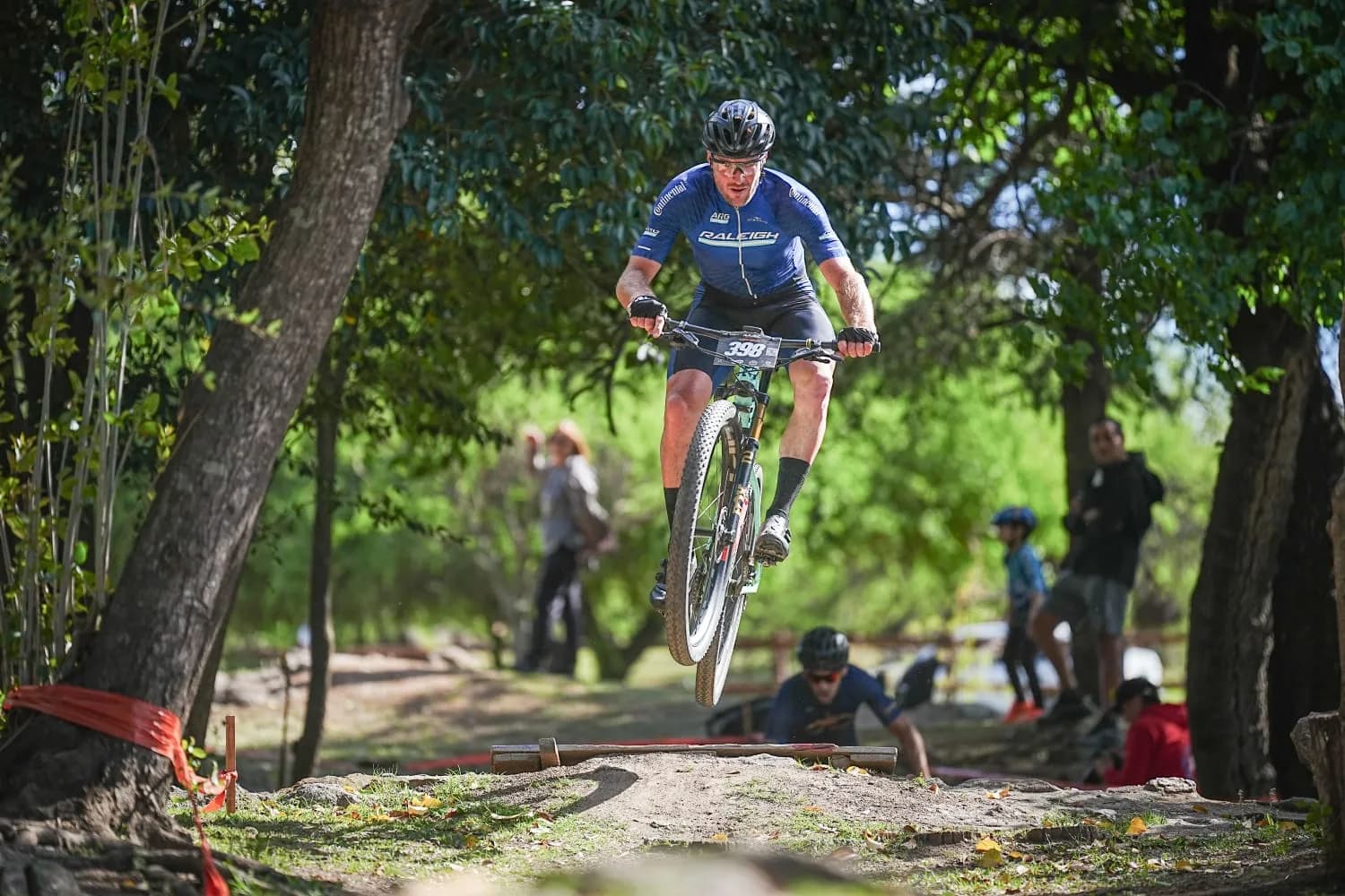Ciclista con la camiseta Raleigh saltando en una carrera de mountain bike